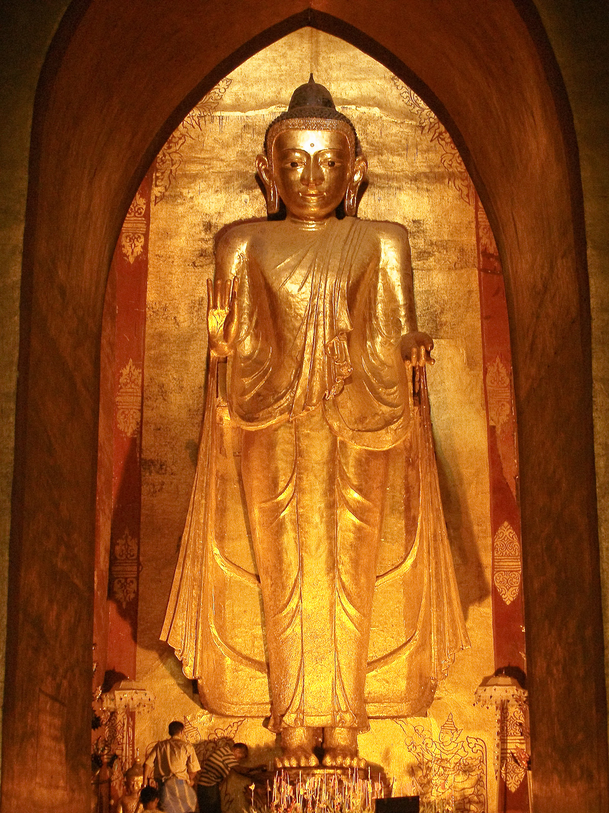a large buddha in an intricate setting with a man sitting