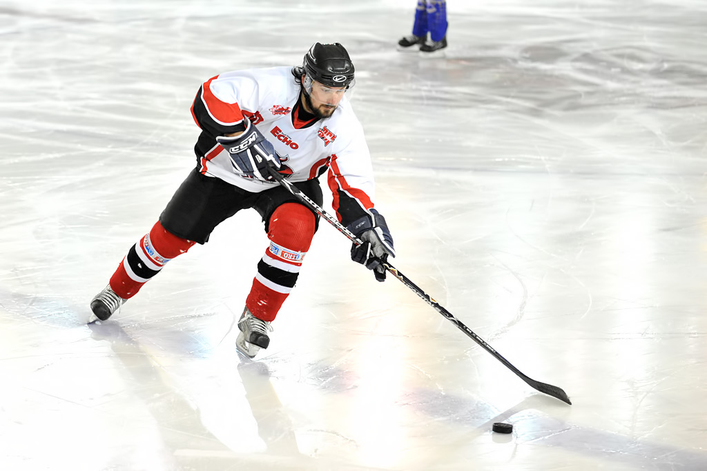 a man is skating on a rink with his hands on the puck