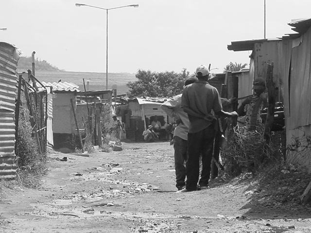 a person standing near some shacks and dirt