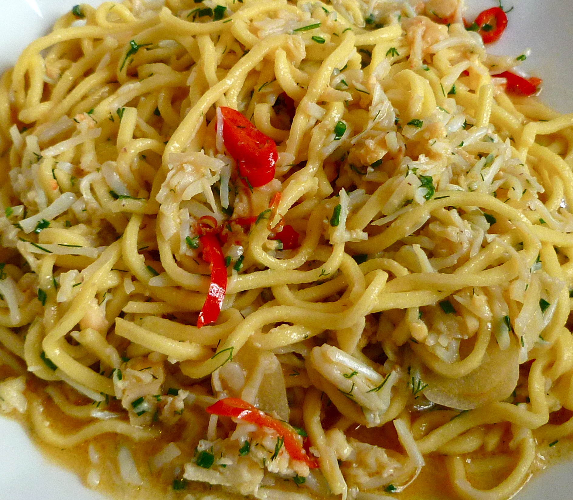 a plate of spaghetti with chicken, parsley and pepper on top