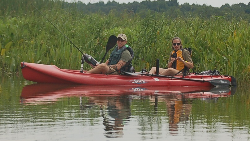 a man and woman sitting in a boat in a swamp