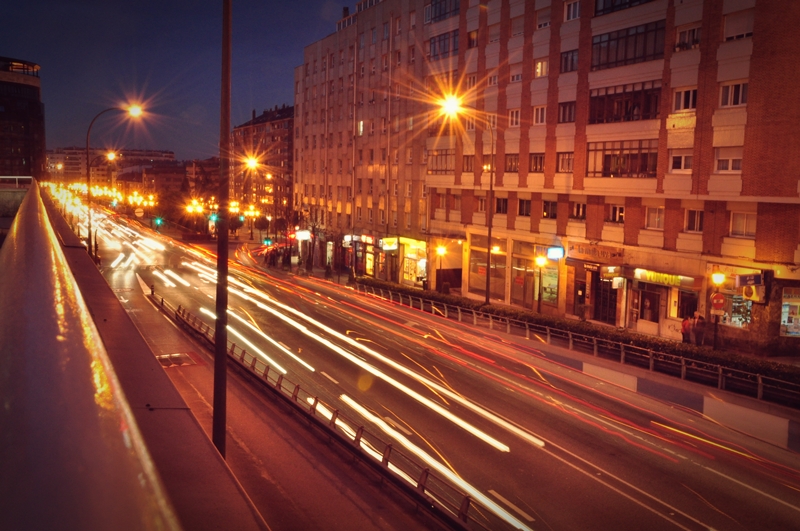 the lights of cars are driving down the street at night