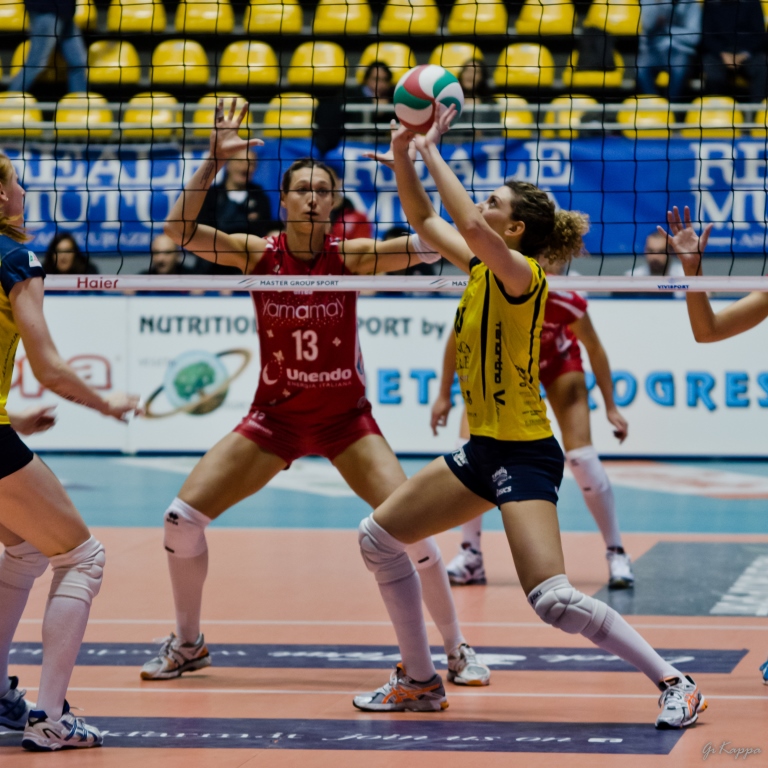 three female volleyball players reach high for the ball