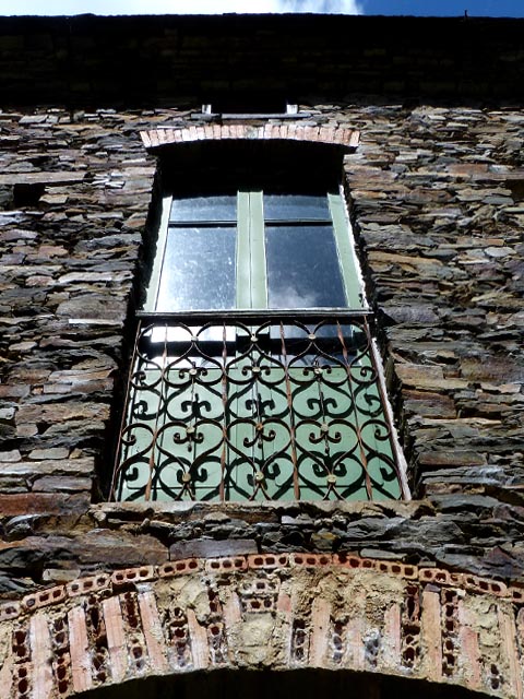 an old brick building with a window and grillwork