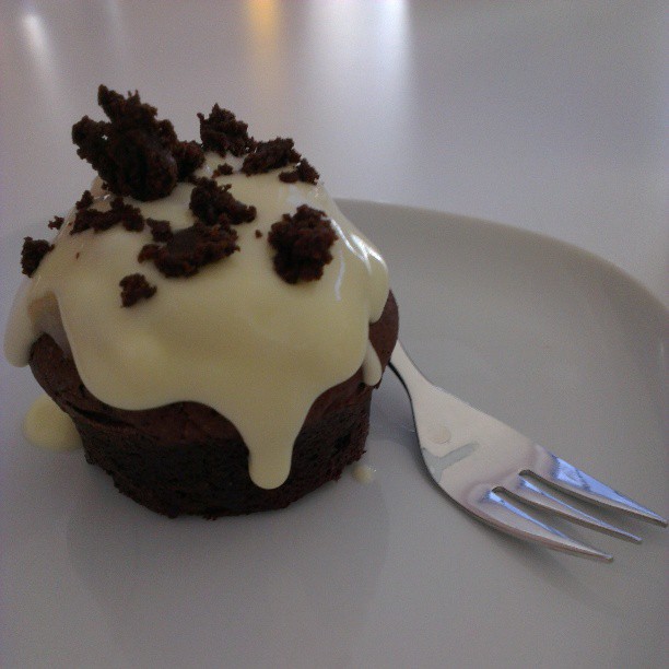 a chocolate cupcake sitting on top of a plate with frosting