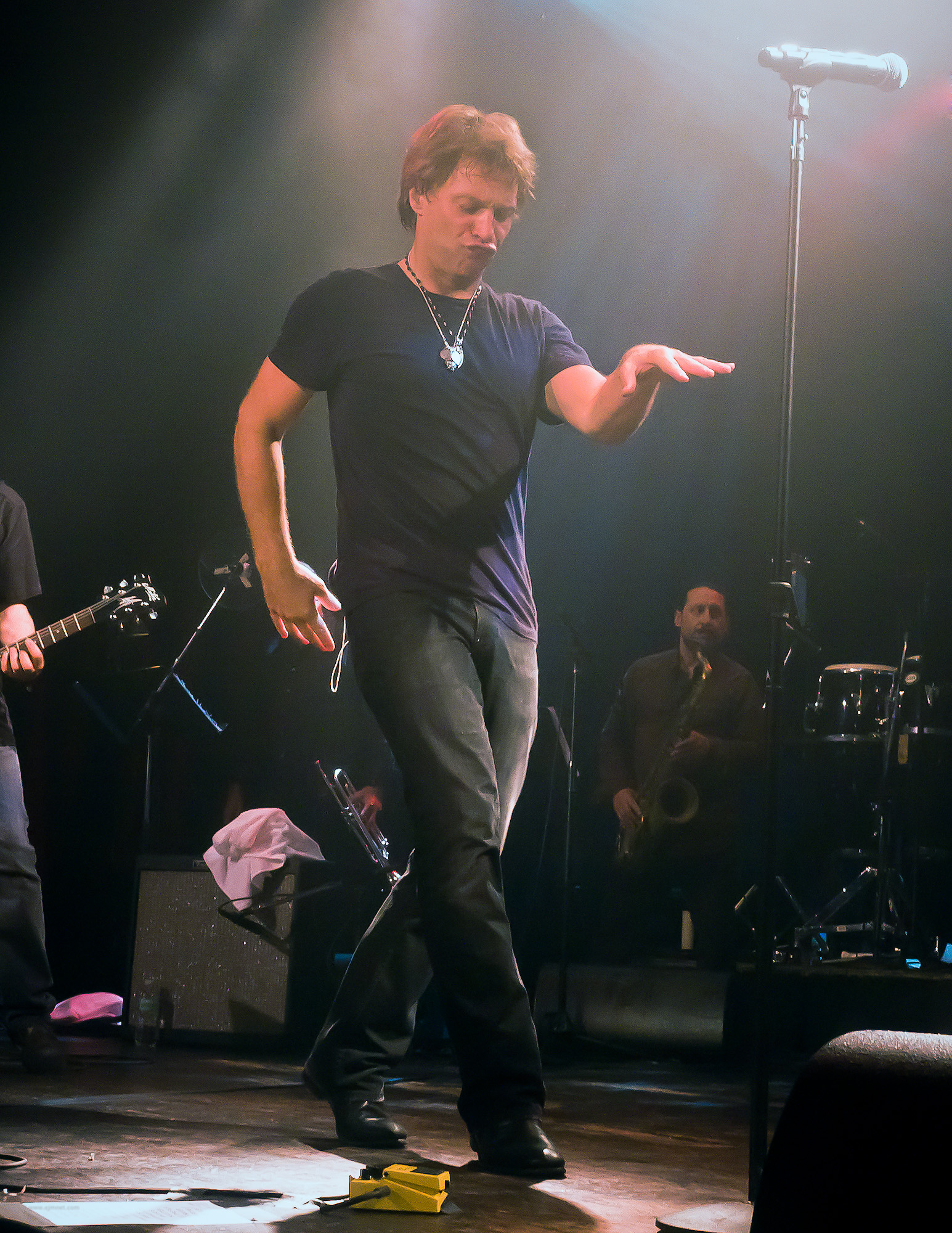 two men on stage one in motion, one standing up with his arms out