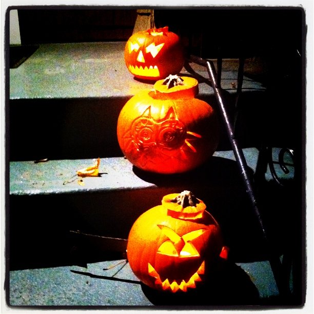 pumpkins carved in the shape of faces on cement steps