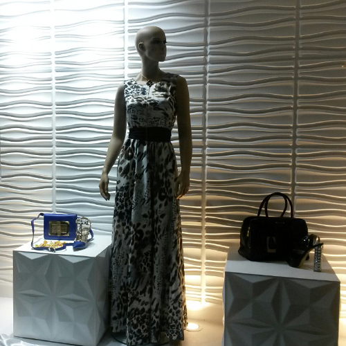 two mannequins in front of a wall with a purse and purse