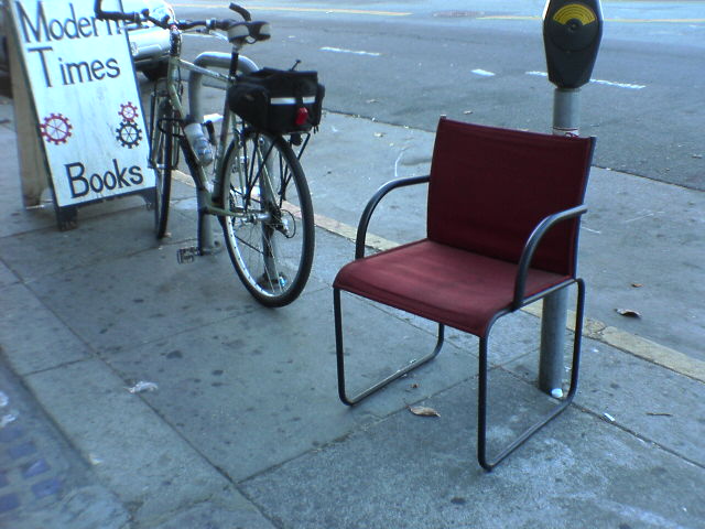 the chair is beside the parking meter next to a book store