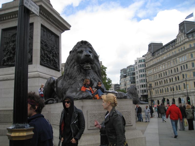 several people stand around a lion statue