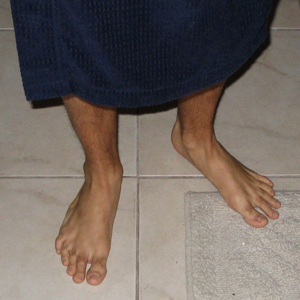 the bare feet of a man standing on a bathroom floor