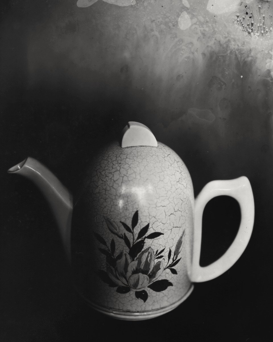 an old fashioned teapot with leaves on the outside