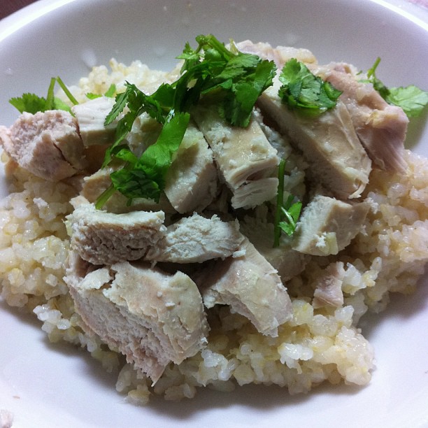 a plate of rice topped with sliced meat and parsley