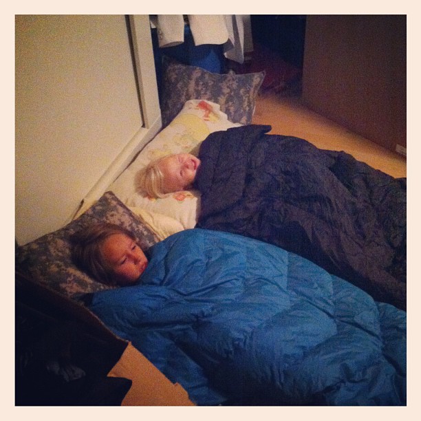 two young children sleeping on top of a blue sheet