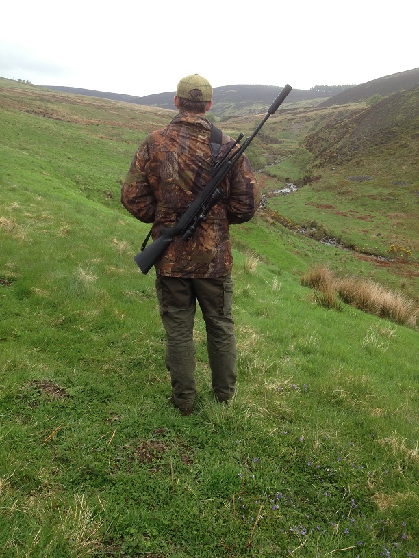 a man with a rifle and a hunting outfit