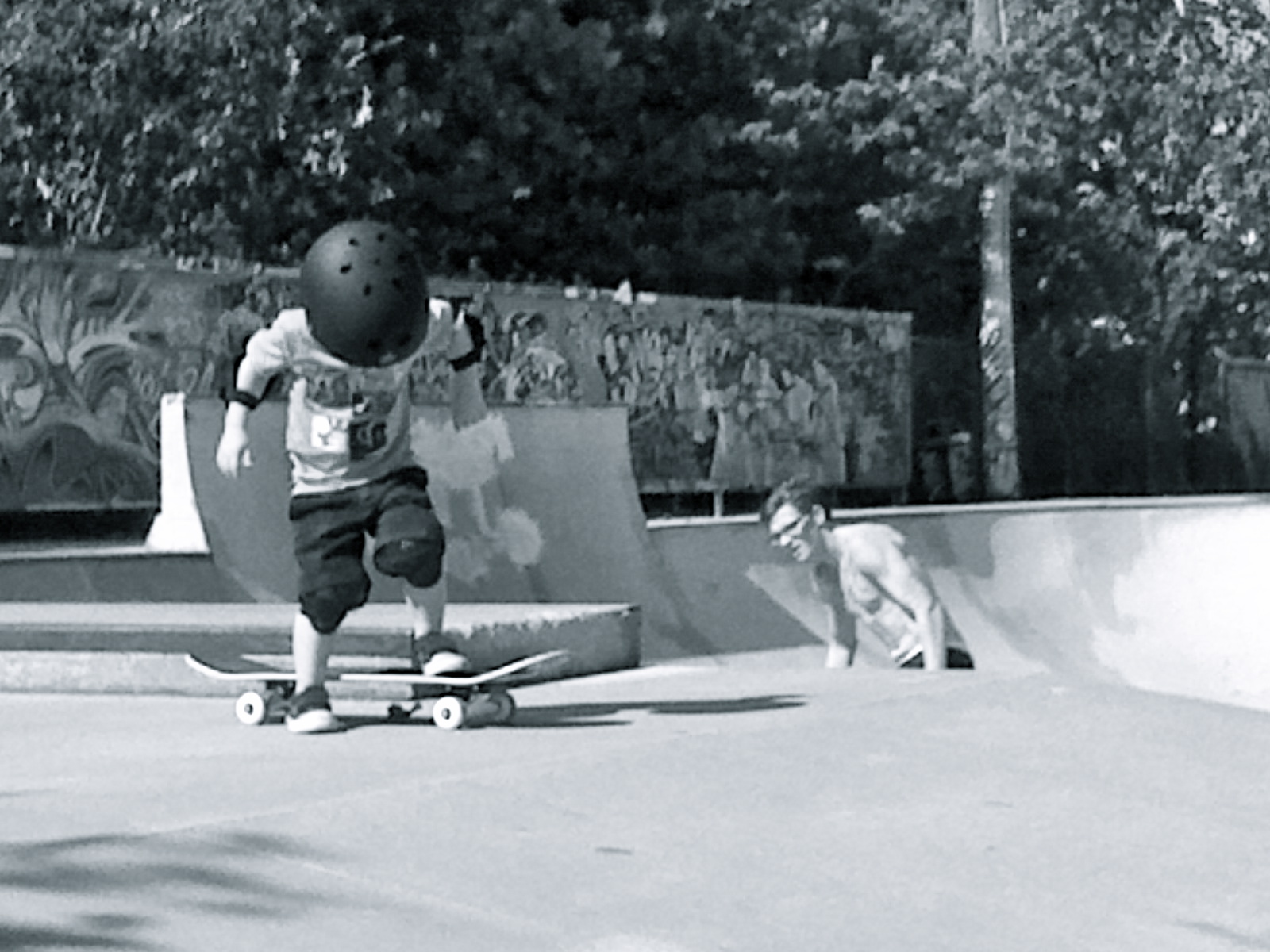 a child skateboards on the pavement as a person squats