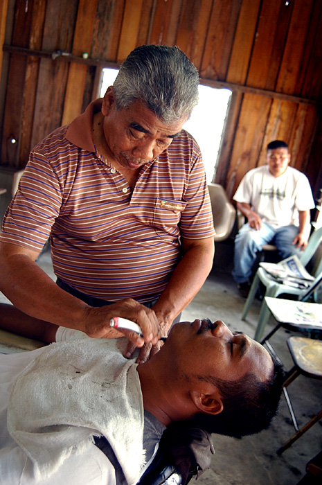 a man getting a haircut while a woman watches