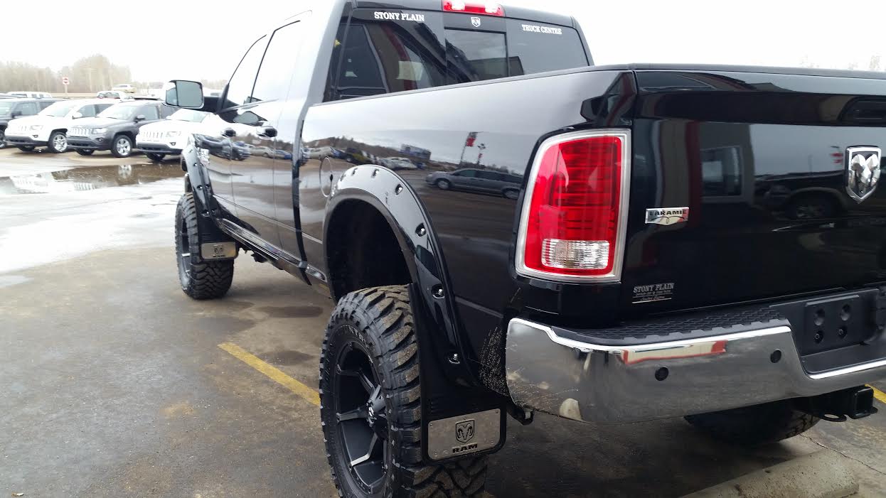 a large black truck parked on a wet parking lot