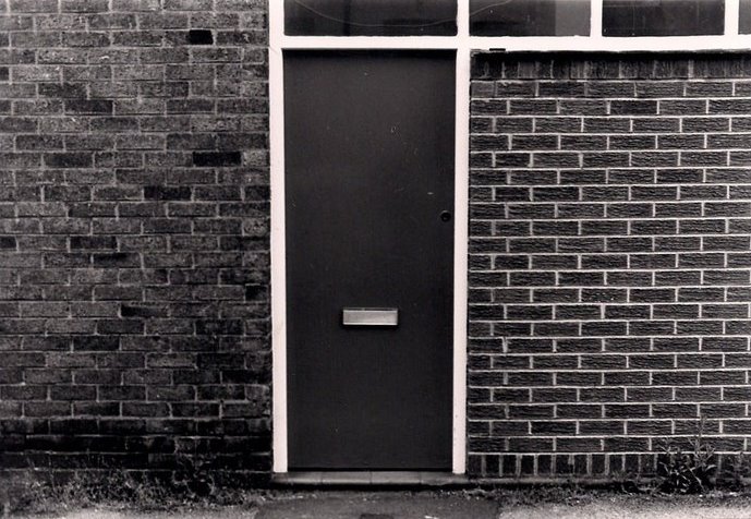 an old fashioned door and black brick wall on a street corner