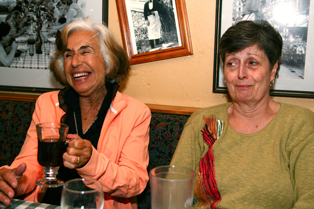 a couple of women sitting at a table drinking soing