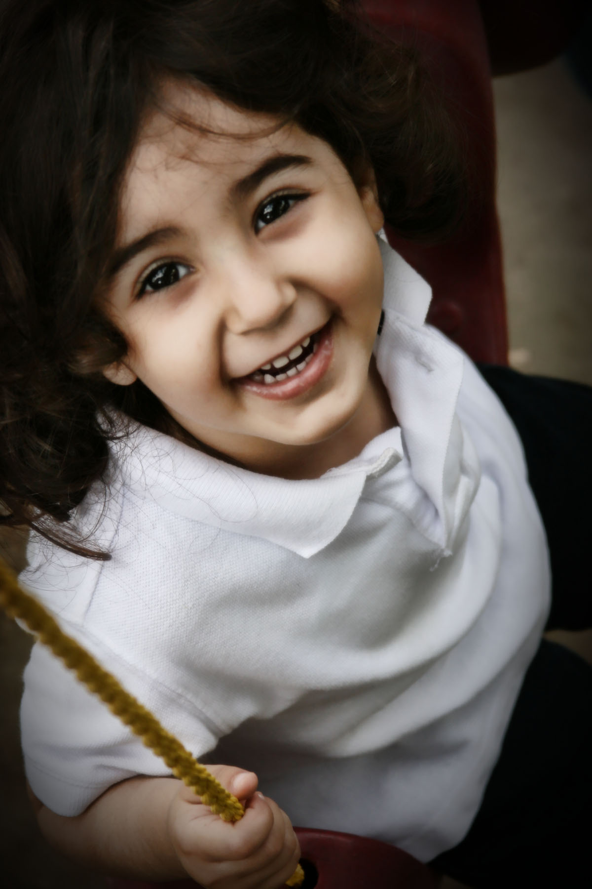 a little girl wearing white shirt holding a pair of scissors