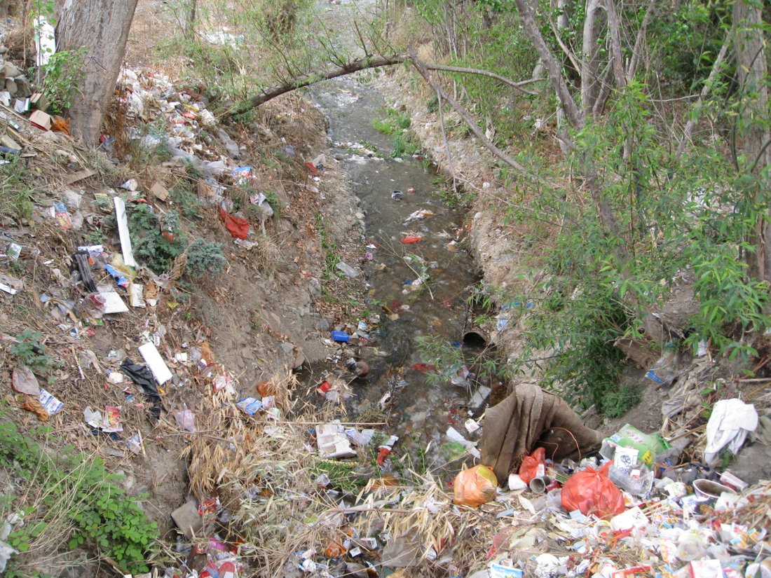 there is trash surrounding the ditch and the road