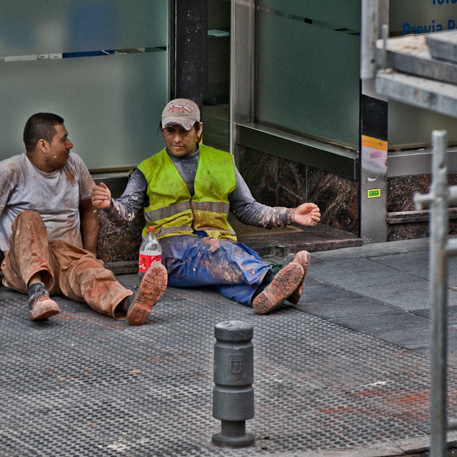 two men sitting on the ground while talking
