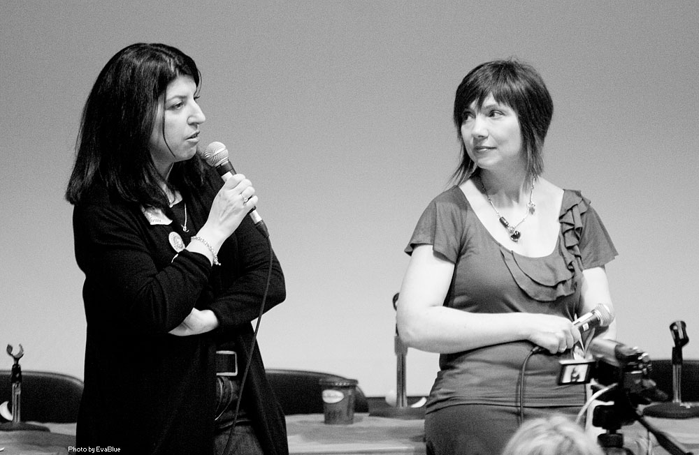 two women speaking in front of a crowd