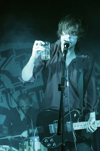 a man holding up a beer in front of a microphone