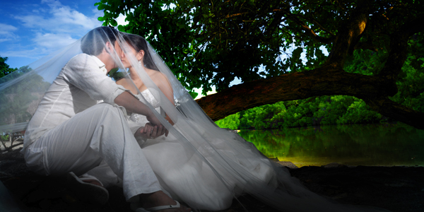 a bride in white is sitting near a tree