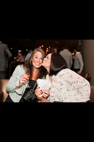 two women are smiling and holding wine glasses together