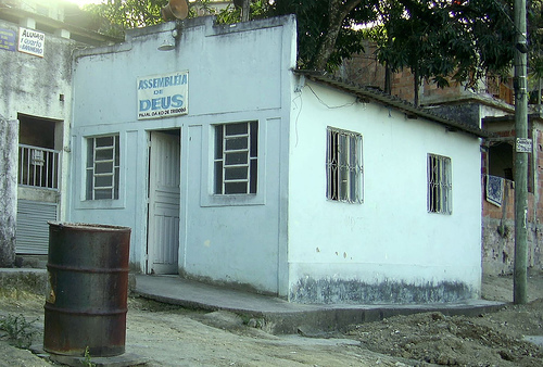 a white building with a black metal barrel on the street