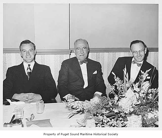 three men seated next to each other at a dinner table