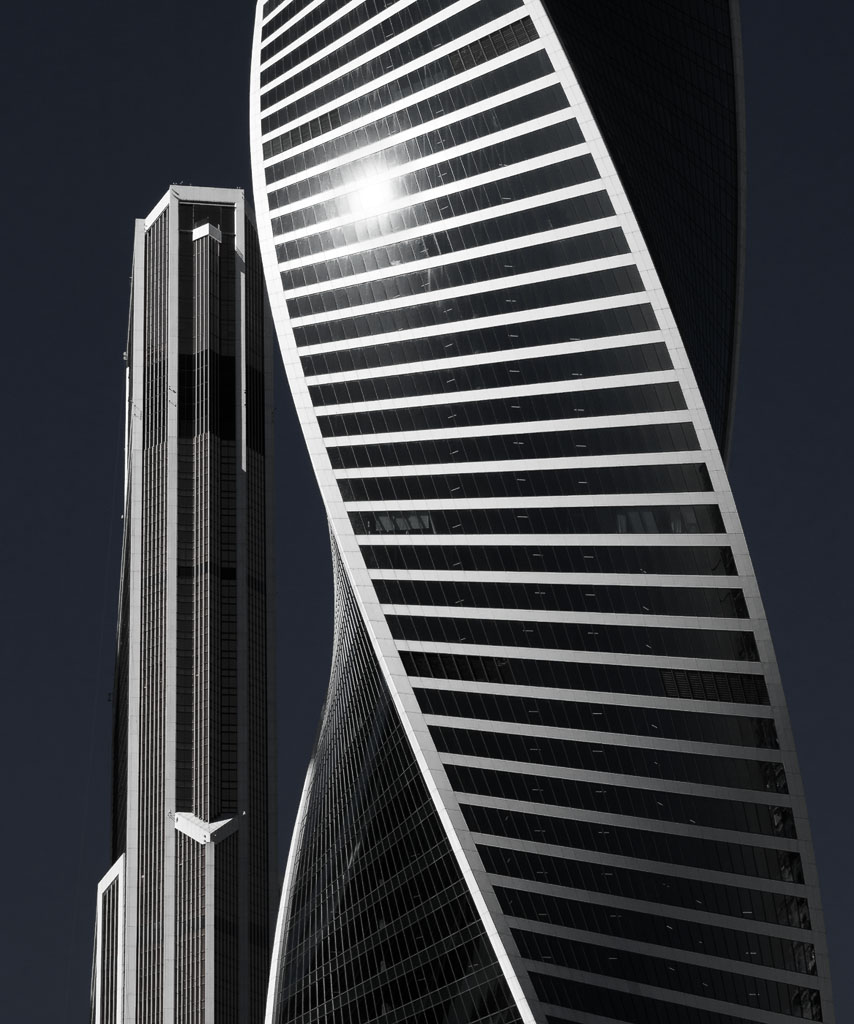 a tall building with a curved design and the light shining on it