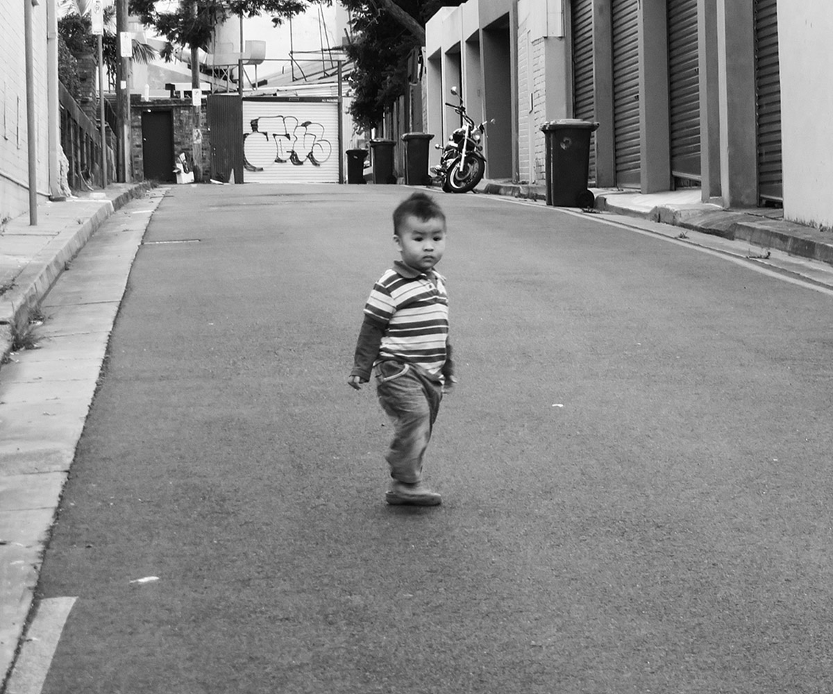 black and white po of small child walking in street