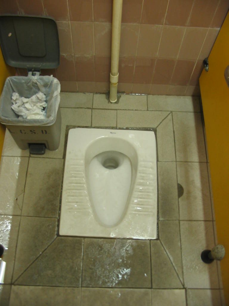 a public toilet in the middle of some dirty tiles