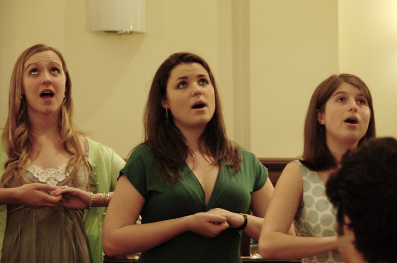 three women standing and holding hands over their mouths