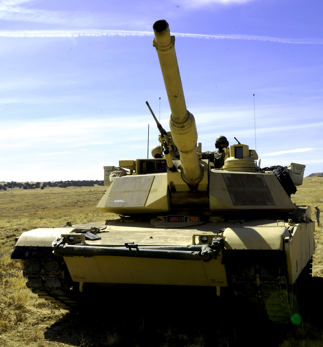 a tank sitting on the field near some people