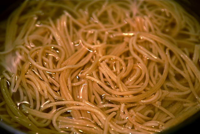 the noodles are being cooked and stirred in a pot