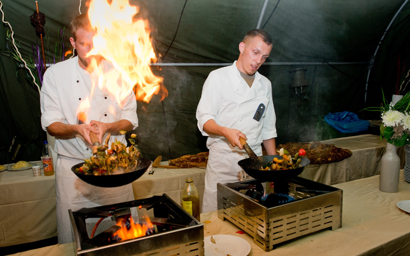 some chefs are preparing some food in large pots