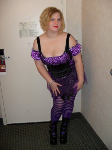a woman wearing purple and black clothing stands in a room