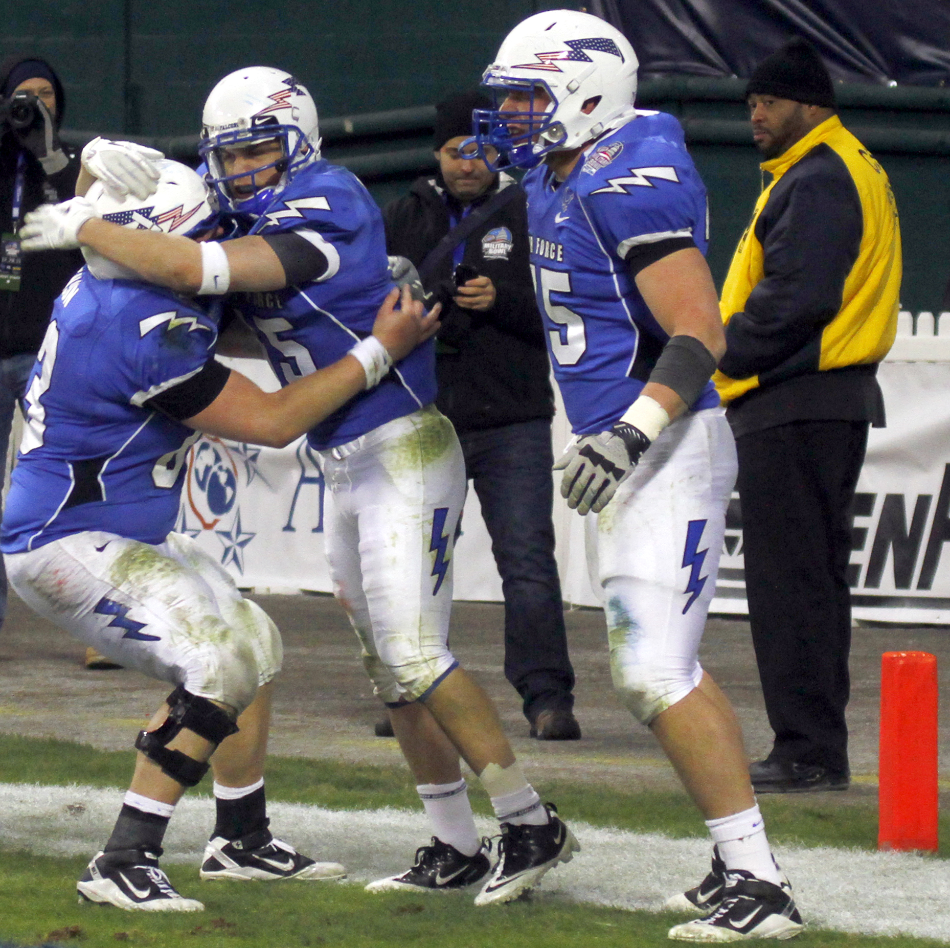 two football players hug on the sidelines of a stadium