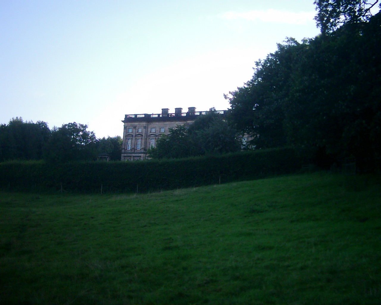 a large building in the background, framed by green grass and trees