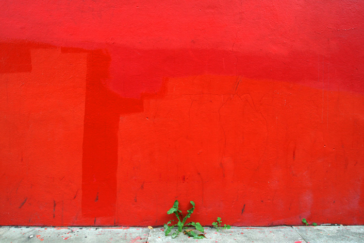 a red wall and bench on a sidewalk