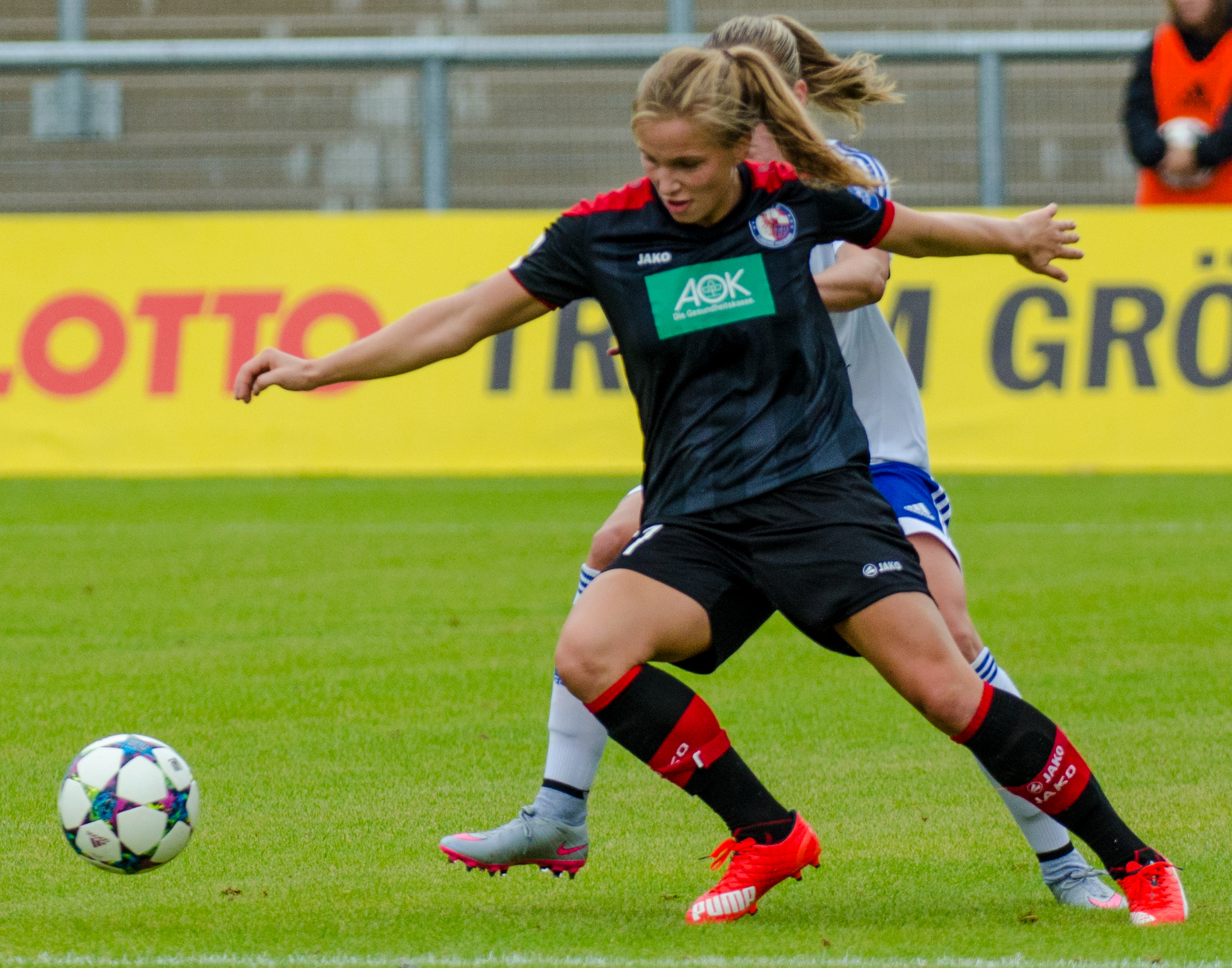 two women trying to kick a soccer ball