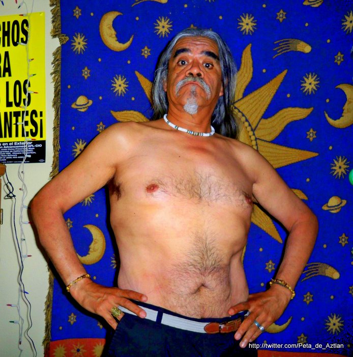 a man with long hair and  standing in front of a wall