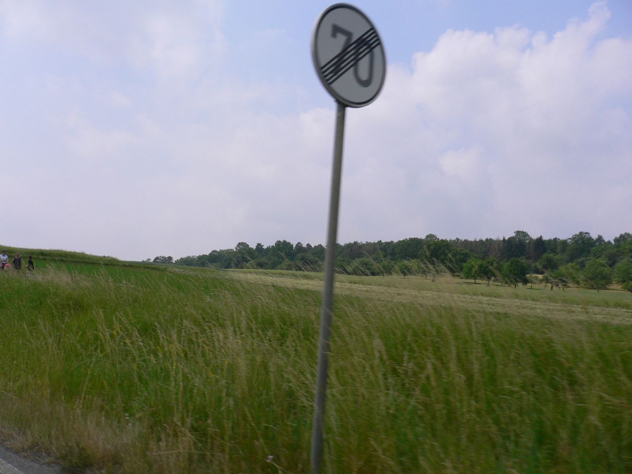 a speed limit sign with people walking in the distance