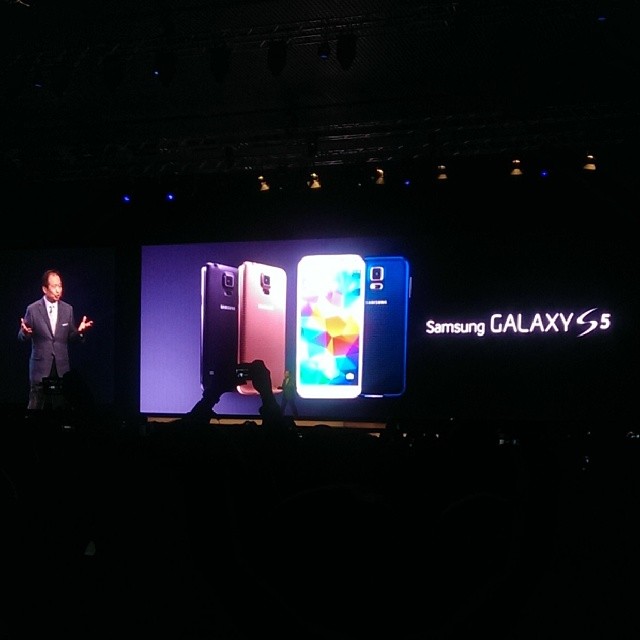 a man stands on stage in front of two smartphones
