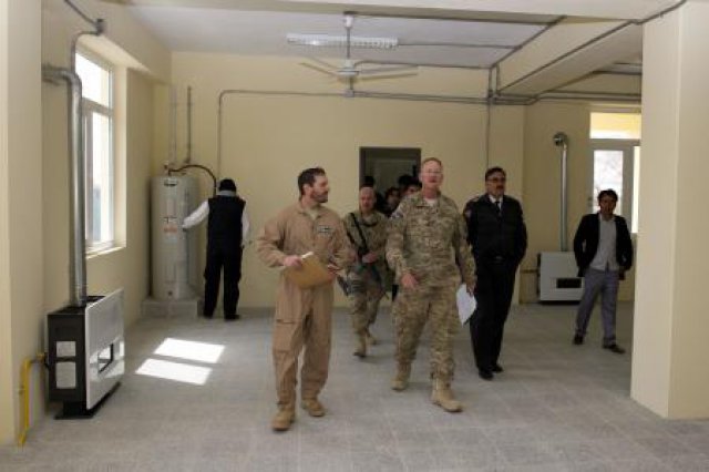 two men in uniforms are walking along a long hallway