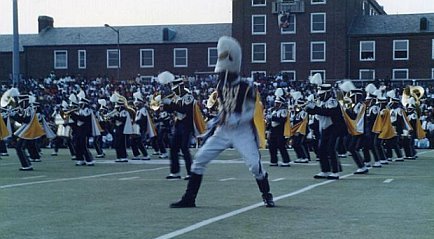marching band playing in an open parking lot with large crowd